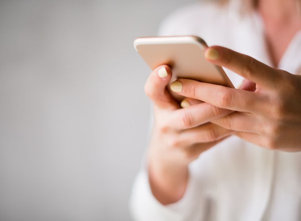 Kvinne holder en mobiltelefon i hånden.