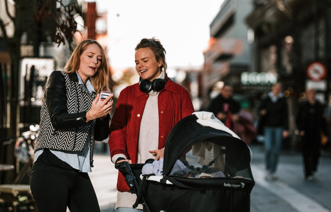 To damer som snakker og ser på mobil